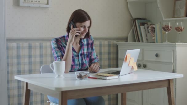 Jeune femme indépendante travaillant à la maison. Brunette femmes parlant en ligne assis à la table en provence intérieur . — Video