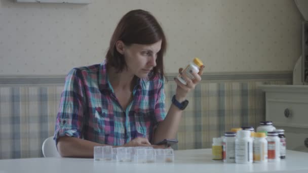 Jonge vrouwelijke sortering en inname van vitaminen zittend aan tafel in de Provence interieur. Vrouwen zorgt voor haar gezondheid — Stockvideo