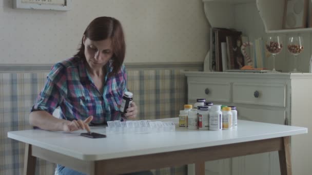 Молодая женщина сортирует и принимает витамины, сидя за столом в интерьере прованса. Женщины заботятся о своем здоровье — стоковое видео