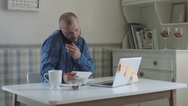 Мужчина-фрилансер совершает покупки с помощью кредитной карты и работает на ноутбуке — стоковое видео