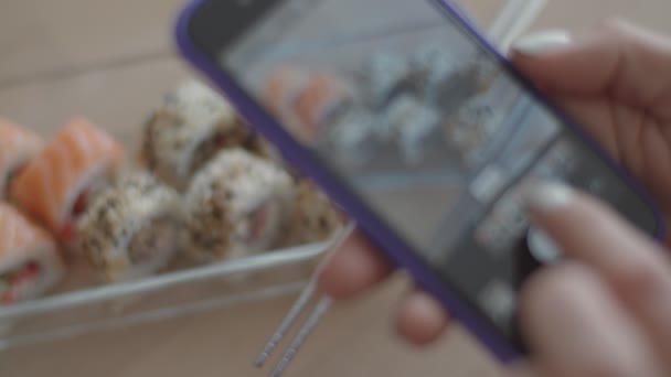 Жінка боку беручи картину суші на своєму телефоні. Вибір кращих фільтрів для фото японської кухні. — стокове відео