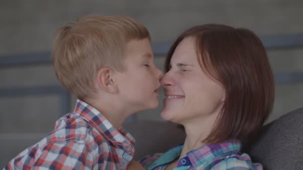 Joyeux jeune mère brune jouant avec fils blond tout-petit assis dans un fauteuil. Femme et garçon riant au ralenti . — Video