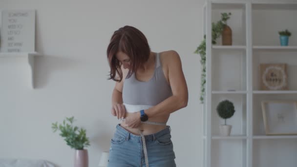 Jeune femme admirant le résultat de la perte de poids tout en portant de vieux jeans dans la chambre. Happy femelle prendre des photos de son ventre après que vous avez perdu du poids . — Video