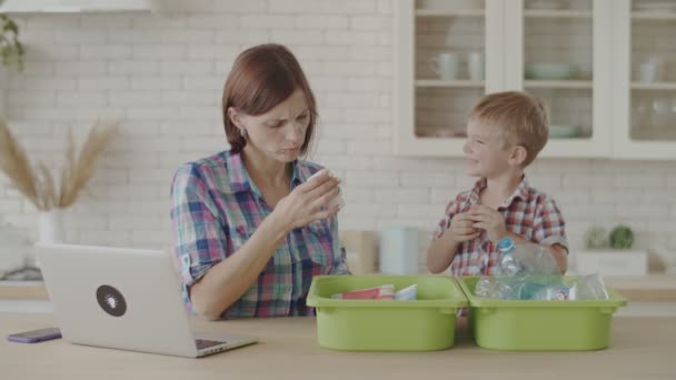 Madre e hijo clasificando residuos de plástico y vidrio para reciclaje. Niño aprendiendo a reciclar plástico. Ecológico ambiente de ahorro familiar . — Vídeo de stock