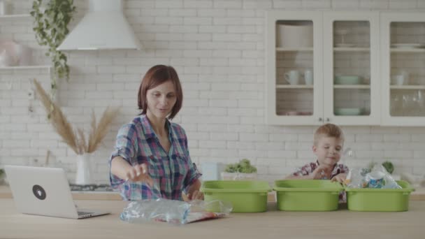 Madre e hijo clasificando residuos de plástico y vidrio para reciclaje. Niño aprendiendo a reciclar plástico. Ecológico ambiente de ahorro familiar . — Vídeo de stock