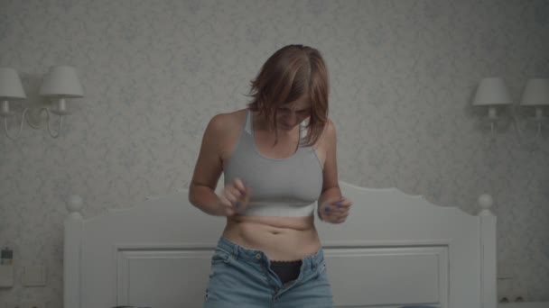 Slow motion van overstuur jonge vrouwen proberen om haar jeans te dragen. Vrouw teleurgesteld in haar lichaam. Gewichtsverlies concept. — Stockvideo