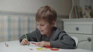 Autistic boy coloring with pencils in slow motion. Kid with autism happy to paint. Autism awareness 