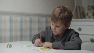 Autistic boy coloring with pencils in slow motion. Kid with autism happy to paint. Autism awareness 