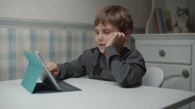 Autistic boy learning online with tablet computer and headphones in slow motion. Kid with autism happy to use gadget. Autism awareness 