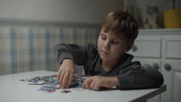 Autystyczne dziecko kończące układankę na stole w zwolnionym tempie. Dziecko z autyzmem rozwiązywanie zagadek układanki. Świadomość autyzmu — Wideo stockowe