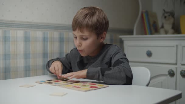 Niño autista completando rompecabezas sobre la mesa en cámara lenta. Niño con autismo clasificando tarjetas. Conciencia del autismo — Vídeos de Stock