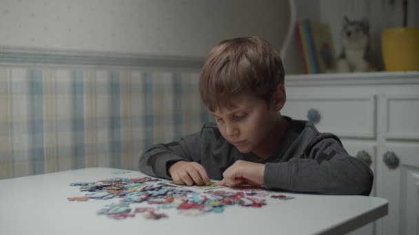 Autistic kid completing jigsaw puzzle on the table in slow motion. Child with autism solving puzzle jigsaw. Autism awareness — Stock Video