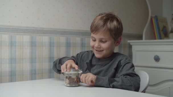 Аутистська дитина їсть здорові закуски в повільному русі, сидячи за столом. Хлопчик задоволений їжею. Поінформованість про аутизм — стокове відео