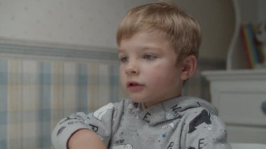 Sarışın çocuğun sağlıklı yiyecekler yediği ve ağır çekimde şarkı söylediği yakın plan.. 