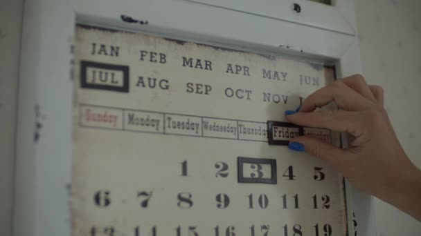 Las mujeres cambian las fechas a mano en el calendario magnético de pared en cámara lenta. Fijación de la fecha del 4 de julio, sábado en calendario . — Vídeos de Stock