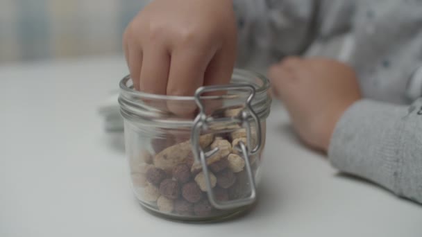 Nahaufnahme der Kinderhand, die in Zeitlupe heidnische Snacks aus der Glasschale nimmt. — Stockvideo