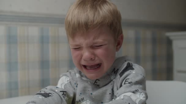 Αναστατωμένο ξανθό αγόρι που κλαίει με συναισθήματα στο πρόσωπό του σε αργή κίνηση. Το κλαψιάρικο παιδί είναι δυστυχισμένο. — Αρχείο Βίντεο