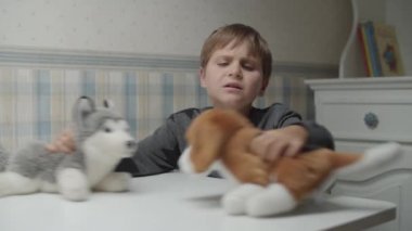 Otistik çocuk ağır çekimde iki yavru köpekle oynuyor. Otizmli çocuk yumuşak köpek oyuncağına sarılıyor. Otizm farkındalığı 