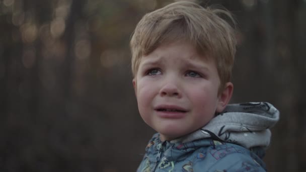 Niño trastornado en chaqueta llorando con lágrimas en el parque de otoño puesta de sol en cámara lenta. Niño llorando y limpiando el desgarro a mano de la cara . — Vídeo de stock