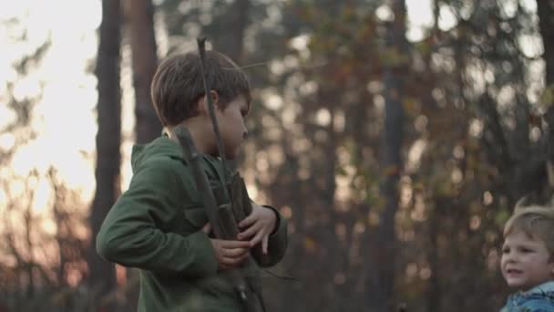 Two boys in jackets collecting dry tree branches in fall park on sunset in slow motion. — Stockvideo