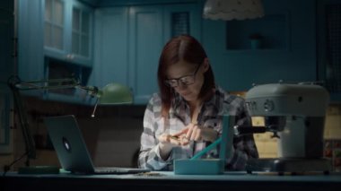 Gözlüklü 30 'lu yaşlardaki genç bir kadın evde bozuk paraları sayıyor. Gece para sayan bir kadın. Kadın gözlüğündeki yansıma.. 