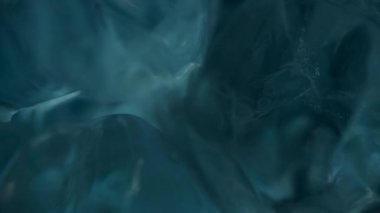 Mavi bardaktaki buz küplerine su dökmenin makro görüntüsü. Mavi ışıkta buzdaki su kabarcıklarını kapat. 