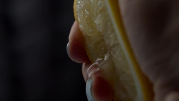 Närbild av kvinnlig handklämmande citronsaft. Hälften av citron frukt klämmer i slow motion makro visa. — Stockvideo