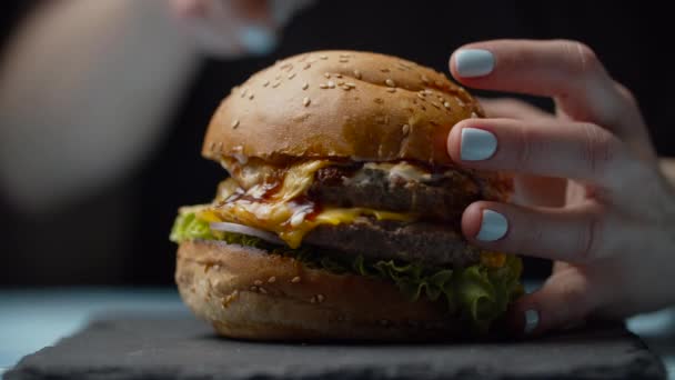 Hamburger délicieux à couper les mains des femmes avec escalope de bœuf double, fromage fondu, laitue et légumes au gros couteau au ralenti . — Video