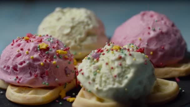 Waffles caseiros com cobertura de palhetas de gelo a cores rotativas. cobertura de pastelaria caindo em bolas de resma de gelo rosa e verde em waffles em câmera lenta . — Vídeo de Stock