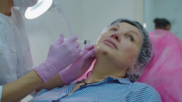 Cosmetologues en gants roses faisant beauté anti-âge injection faciale à la femme adulte avec seringue. Procédure d'injection de beauté au ralenti . — Video