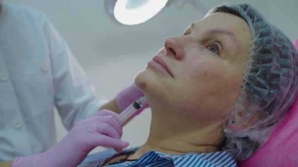 Cosmetologen in roze handschoenen maken schoonheid anti-aging gezichtsinjectie bij volwassen vrouw met spuit. Beauty injectieprocedure in slow motion. — Stockvideo