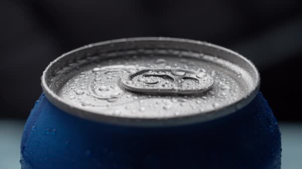 Close up de refrigerante azul molhado frio pode top girando sobre fundo escuro em câmera lenta. Cola azul pode virar . — Vídeo de Stock