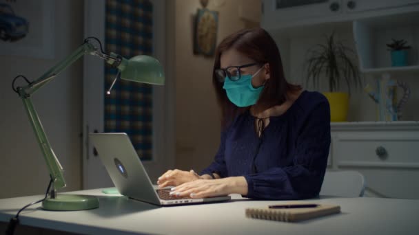 Mujer joven de 30 años en máscara protectora verde leer bien nuevo en el ordenador portátil, se quita la máscara médica de la cara y gafas y se escapó . — Vídeo de stock