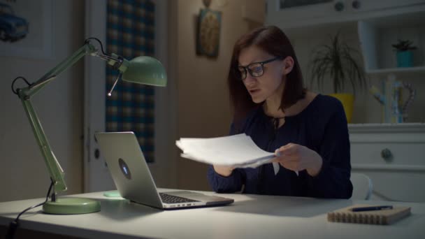 A 30-as éveiben járó fiatal nő egy halom papírt mutat a laptopnak, és panaszkodik a sok munka miatt. Belefáradtam, hogy a dolgozó nő ingerülten gesztikulál dokumentumokkal a kezében.. — Stock videók