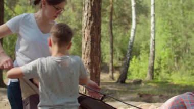 İki kadın ve iki çocuk yaz kampında ormanda tatil yapıyorlar. İki anne ve iki oğuldan oluşan mutlu bir aile kamp için çadır kurmuş. Yavaş çekim, sabit çekim..