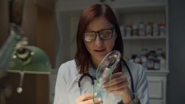 Trabajar desde casa médico de 30 años muestra cómo usar el inhalador. Mujer con abrigo médico blanco con estetoscopio en el cuello hablando mirando a la cámara . — Vídeos de Stock