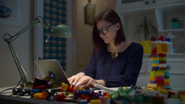 Junge irritierte 30er arbeiten von zu Hause aus mit einem Stapel Kinderspielzeug auf dem Arbeitstisch mit Laptop und Dokumenten. Wütende Frau wirft Spielzeug vom Arbeitstisch. — Stockvideo