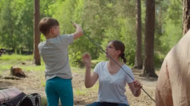 İki kadın ve iki çocuk yaz kampında ormanda tatil yapıyorlar. İki anne ve iki oğuldan oluşan mutlu bir aile kamp için çadır kurmuş. Yavaş çekim, sabit çekim..