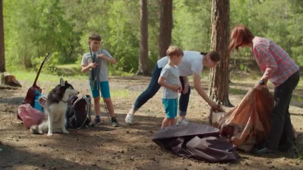 Deux femmes et deux garçons ayant des vacances d'été en camping dans la forêt. Heureuse famille de deux mères et deux fils mis en place tente pour le camping. Ralenti, coup de steadicam . — Video