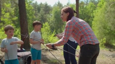 İki kadın ve iki çocuk yaz kampında ormanda tatil yapıyorlar. İki anne ve iki oğuldan oluşan mutlu bir aile kamp için çadır kurmuş. Yavaş çekim, sabit çekim..