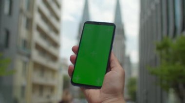 Şehrin caddesinde üzerinde kromakey olan kadın cep telefonu ekranı. Dışarıda yeşil cep telefonu ekranına dokunan kadın..