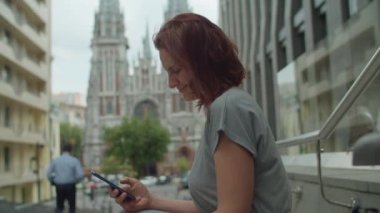 Kablosuz kulaklıklı, sokakta cep telefonu kullanan 30 'lu yaşlardaki genç bir kadın. Sokakta cep telefonuyla internette sörf yapan bir kadın..