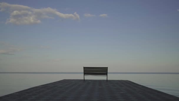 Mladá třicátnice v černých šatech běží a při západu slunce skáče na lavičku na břehu řeky. Jedna osoba u večerního jezírka. — Stock video