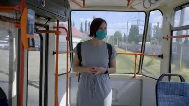 Mujer joven en máscara de protección facial cabalgando en transporte público. Mujer con máscara facial en un tren urbano vacío. Tranvía urbano por la calle . — Vídeos de Stock