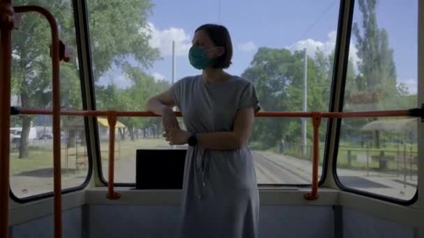 Jonge vrouw in gezichtsbescherming masker rijden in het openbaar vervoer. Vrouw met gezichtsmasker in lege stadstrein. Stedelijke tram rijden de straat. — Stockvideo