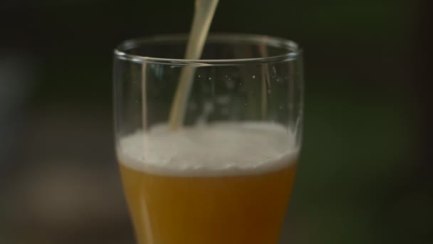Закрыть вращающееся стекло, наливая пиво и пену в замедленной съемке — стоковое видео