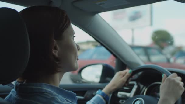 Joven mujer de 30 años conduciendo un coche en la ciudad. Vista lateral del conductor femenino sosteniendo el volante . — Vídeo de stock