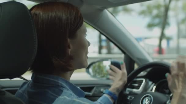 Young 30s woman dancing and singing while driving car in the city. Side view of female driver dancing with hands on steering wheel. — Stock Video