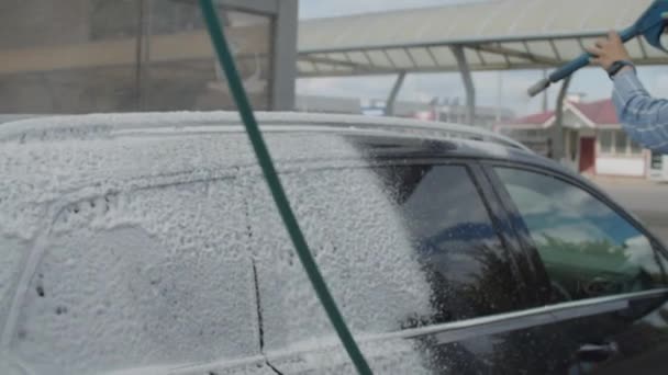 Jeune femme trentenaire laver sa voiture familiale en libre-service lavage de voiture. Femme lave l'automobile avec la mousse et l'eau à l'extérieur. — Video