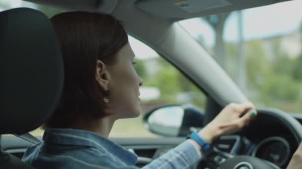 Giovane donna anni '30 alla guida di auto in città. Vista laterale del conducente femmina che tiene il volante. — Video Stock